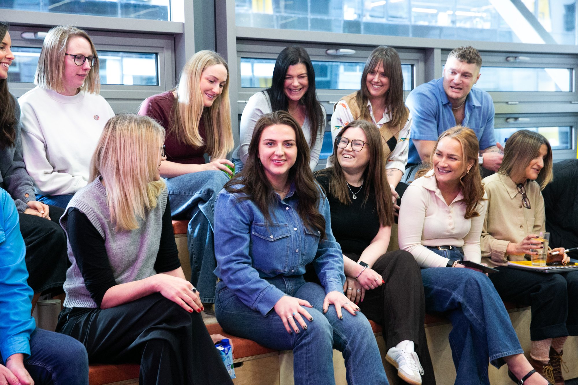 A group of colleagues sitting on benches, discussing ideas with energy and enthusiasm.
